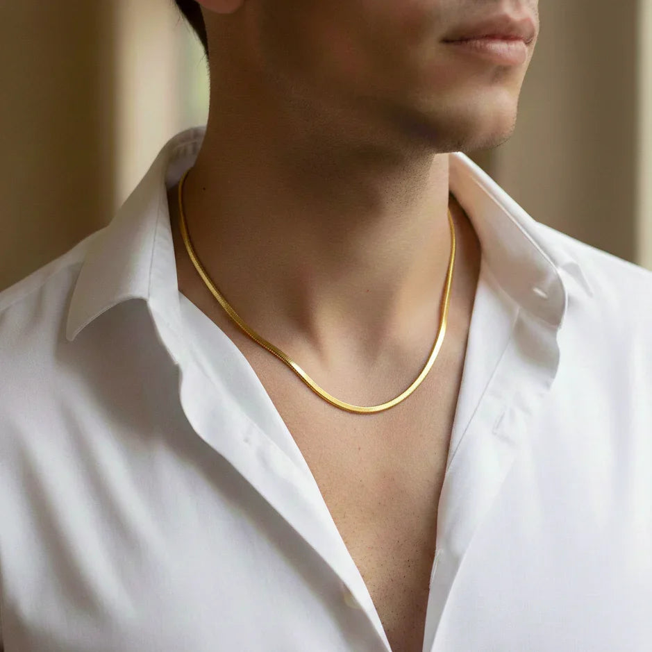 Man wearing a gold herringbone necklace with open white shirt