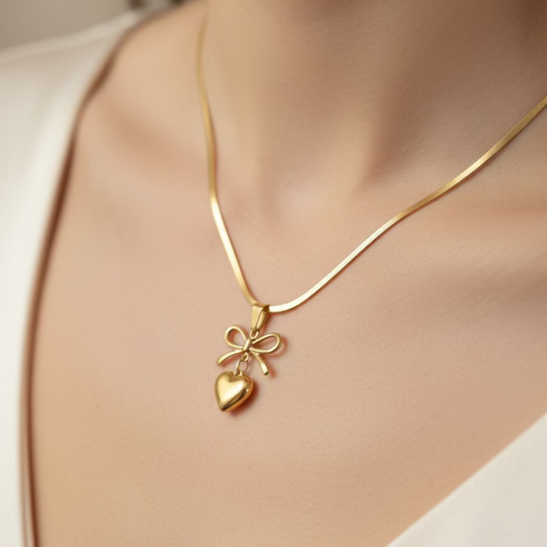 Gold necklace with heart and bow pendant worn by woman, anti-tarnish jewelry close-up