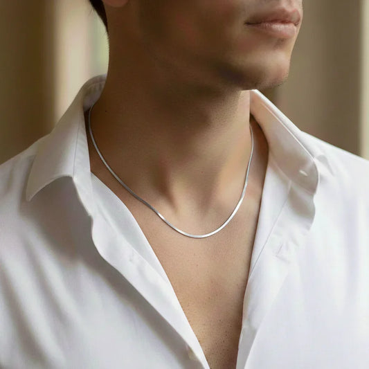 Man wearing a sleek silver necklace with an open-collar white shirt