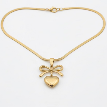 Gold necklace with a bow and heart pendant on white background, anti-tarnish jewelry