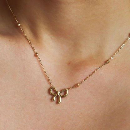 Gold bow pendant necklace on woman's neck, delicate anti-tarnish jewelry