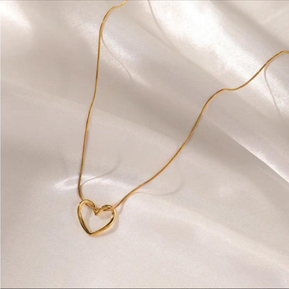 Gold heart pendant necklace on soft white satin fabric background